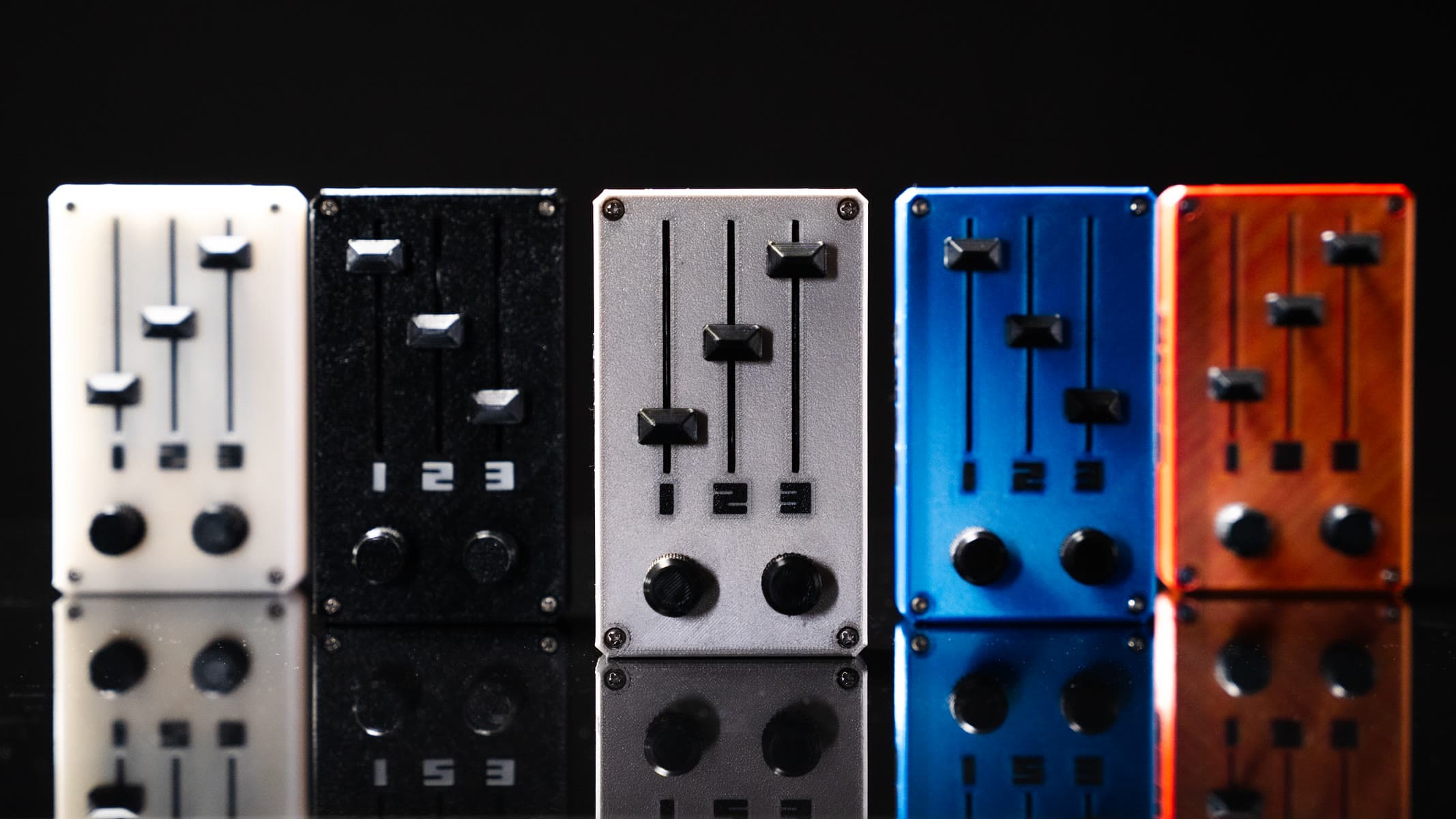 Cinco KNOB en fila sobre fondo negro con reflejo: blanco, negro, plateado, azul y cobrizo